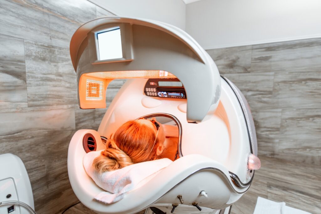 Woman lying in the spa capsule having relaxation, rejuvenation and color therapy in the beauty salon